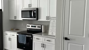 A modern kitchen with white cabinets, a black stove, and a microwave. - Family Fun Getaway, Spacious, Cozy & Kid-Friendly (Ocala)