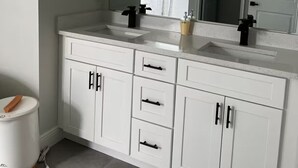 A bathroom with white cabinetry, two sinks, a mirror, and a light fixture above the mirror. - Family Fun Getaway, Spacious, Cozy & Kid-Friendly (Ocala)