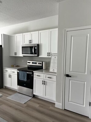 Una cocina moderna con armarios blancos, una estufa negra y un microondas.