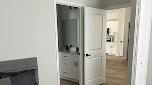 A bedroom with a bed, a dresser, and an open door leading to a kitchen area. - Family Fun Getaway, Spacious, Cozy & Kid-Friendly (Ocala)