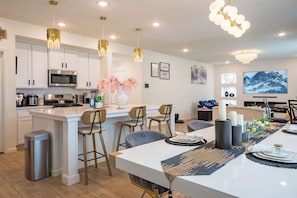 A modern kitchen with white cabinets, stainless steel appliances, and a central island with bar stools. - Beautiful, Spacious 5 bedrooms for large group (Fresno)