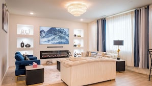 Uma sala de estar moderna com lareira, uma televisão grande e um candelabro.