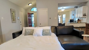 Ein Schlafzimmer mit einem großen Bett, einer schwarzen Ledersofa und einem kleinen runden Tisch.
