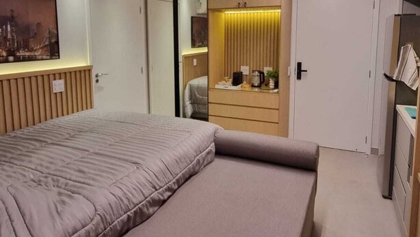 A modern bedroom with a large bed, a desk, and a wardrobe.