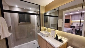 A modern bathroom with a glass-enclosed shower, a vanity with a sink, and a toilet.