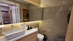 A modern bathroom with a large mirror, a sink, and a toilet.