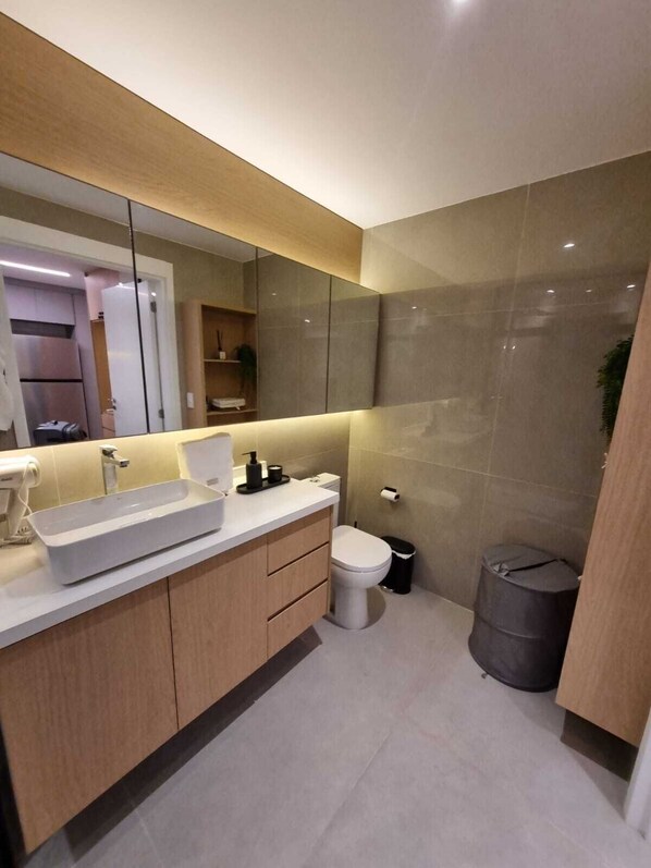 Ein modernes Badezimmer mit großem Spiegel, Waschbecken und Toilette.