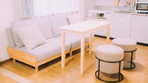 A modern living room with a sofa, a wooden table, and two ottomans. - Showa Bloom · Near Shinjuku Station (Tokyo)