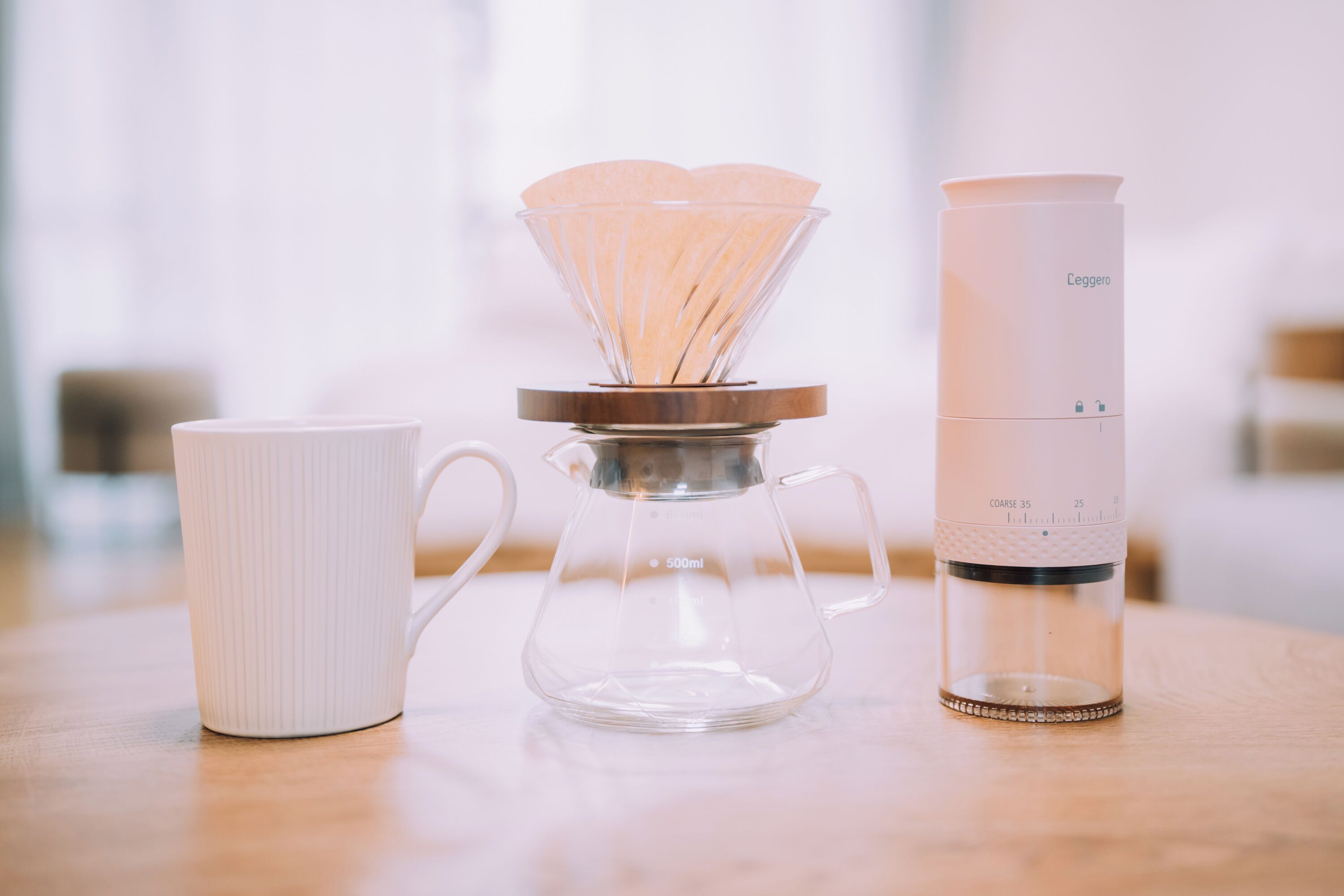 A coffee maker, a white mug, and a water dispenser on a wooden table.