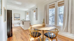 Una cucina moderna con zona pranzo, pavimento in legno e ampie finestre con tende.