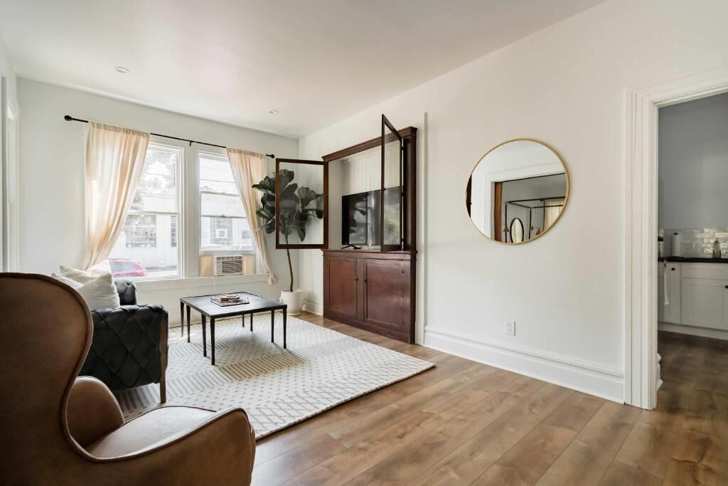 Una sala de estar moderna con un sofá, una mesa de centro, un tapete, un mueble y un espejo.