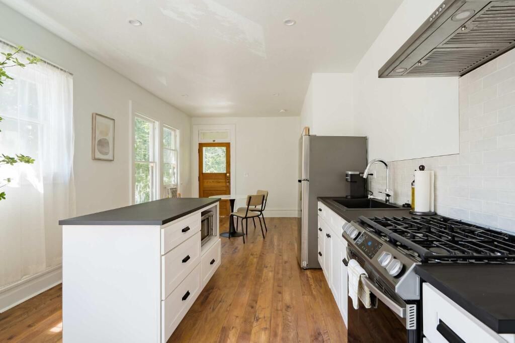 A modern kitchen with white cabinetry, a black countertop, and a stainless steel stove.