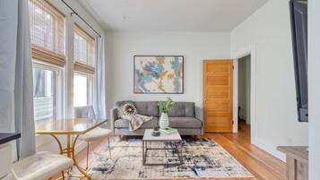 A modern living room with a sofa, coffee table, and a painting on the wall.