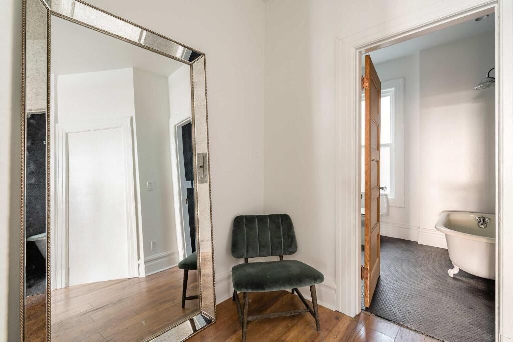 Una habitación con un espejo grande, una silla y un baño con bañera.