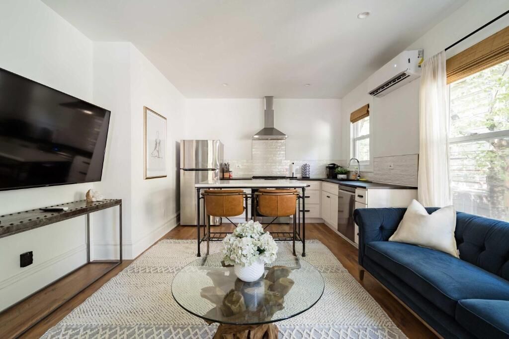 A modern kitchen with a dining area, a sofa, and a TV.