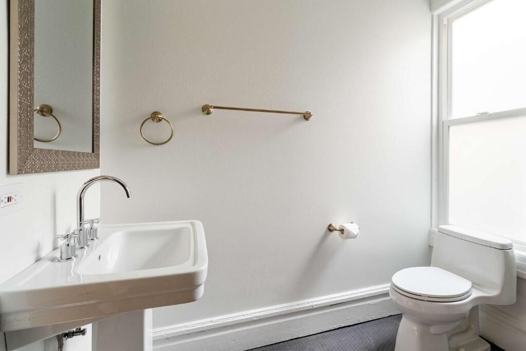 A bathroom with a white sink, a toilet, a mirror, and a towel rack.