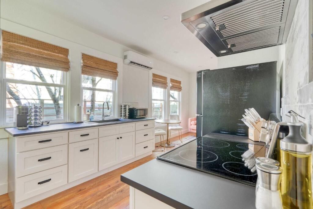 A modern kitchen with white cabinets, a black stove, and a window with a view.