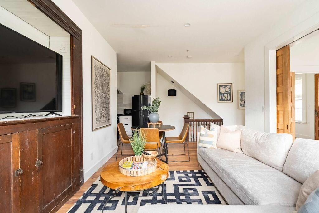 A living room with a sofa, a coffee table, and a TV. There is a staircase leading to another room.
