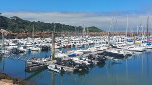 A marina with numerous boats docked, calm water, and a hilly landscape in the background. - Maner roz by Interhome (Trebeurden)