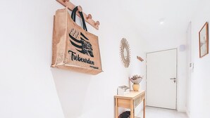 A hallway with a wooden bench, a white door, and a large brown paper bag hanging on the wall. - Maner roz by Interhome (Trebeurden)