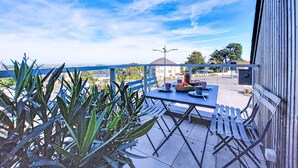 An outdoor patio with a table and chairs, a view of a parking lot, and a building in the background. - Maner roz by Interhome (Trebeurden)