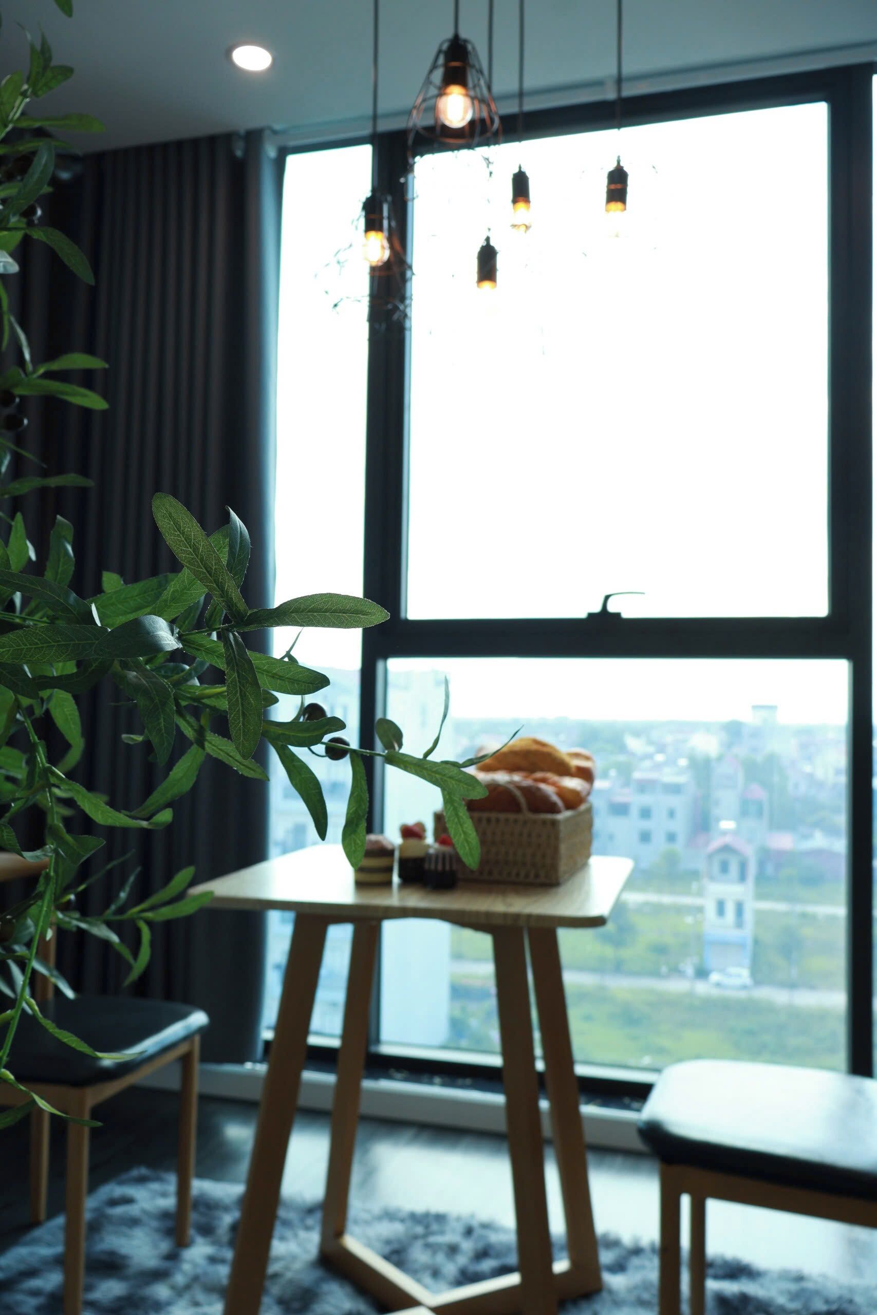 Una habitación con un ventanal grande, una mesa con pan y una planta.