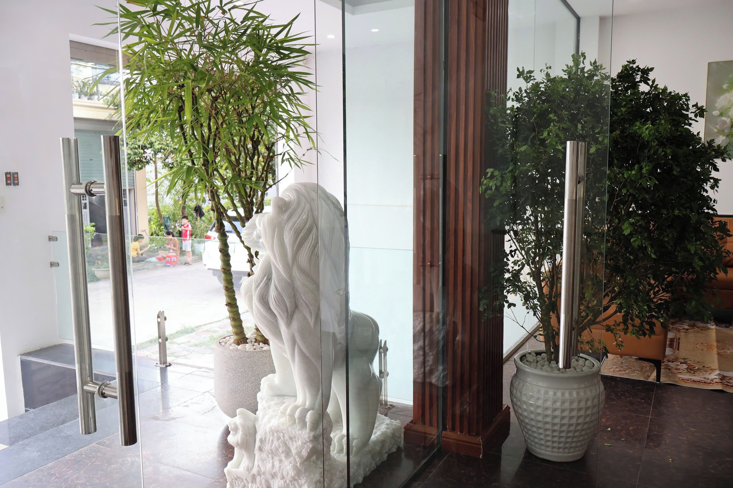 A reception area with a glass door, a white statue, and potted plants.