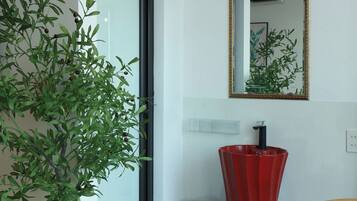 A modern interior with a potted plant, a red vase, and a table with two desserts.