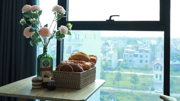 A modern room with a large window, a table with a vase of flowers, and a basket of bread. - The Grand Diamond C Hotel (Nenh)