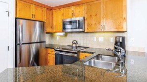 A kitchen with wooden cabinets, stainless steel appliances, granite countertops, and a double sink.