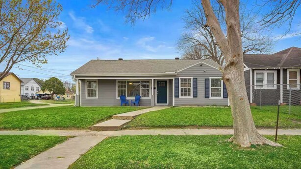 A single-story house with a front porch, a small front yard, and a tree in the foreground. - Orbital Oasis: Dual Living near NASA (Baytown)