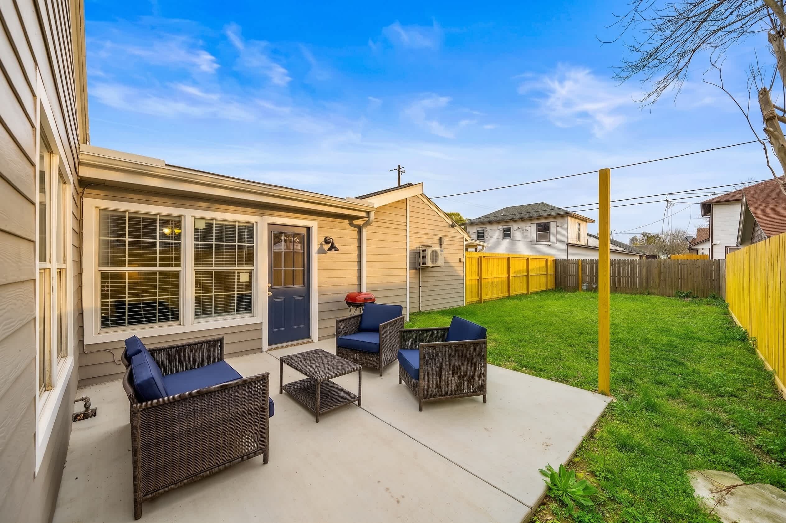 A backyard patio with wicker furniture and a barbecue grill.