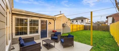 A backyard patio with wicker furniture and a barbecue grill.