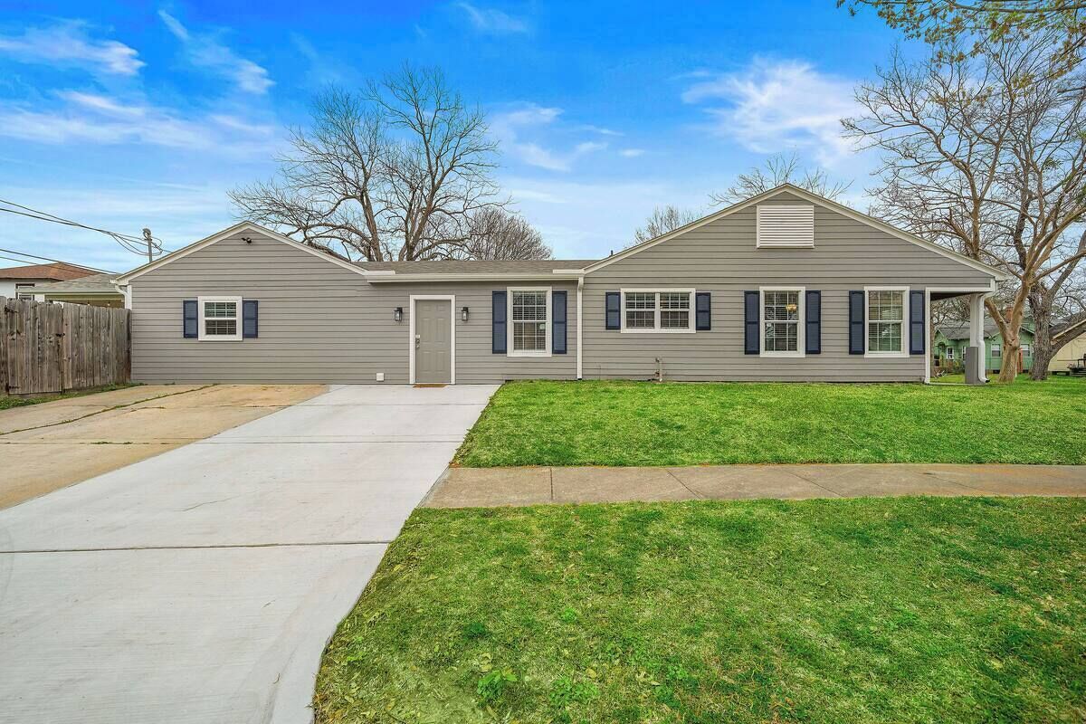A two-story house with a front yard, a driveway, and a wooden fence.