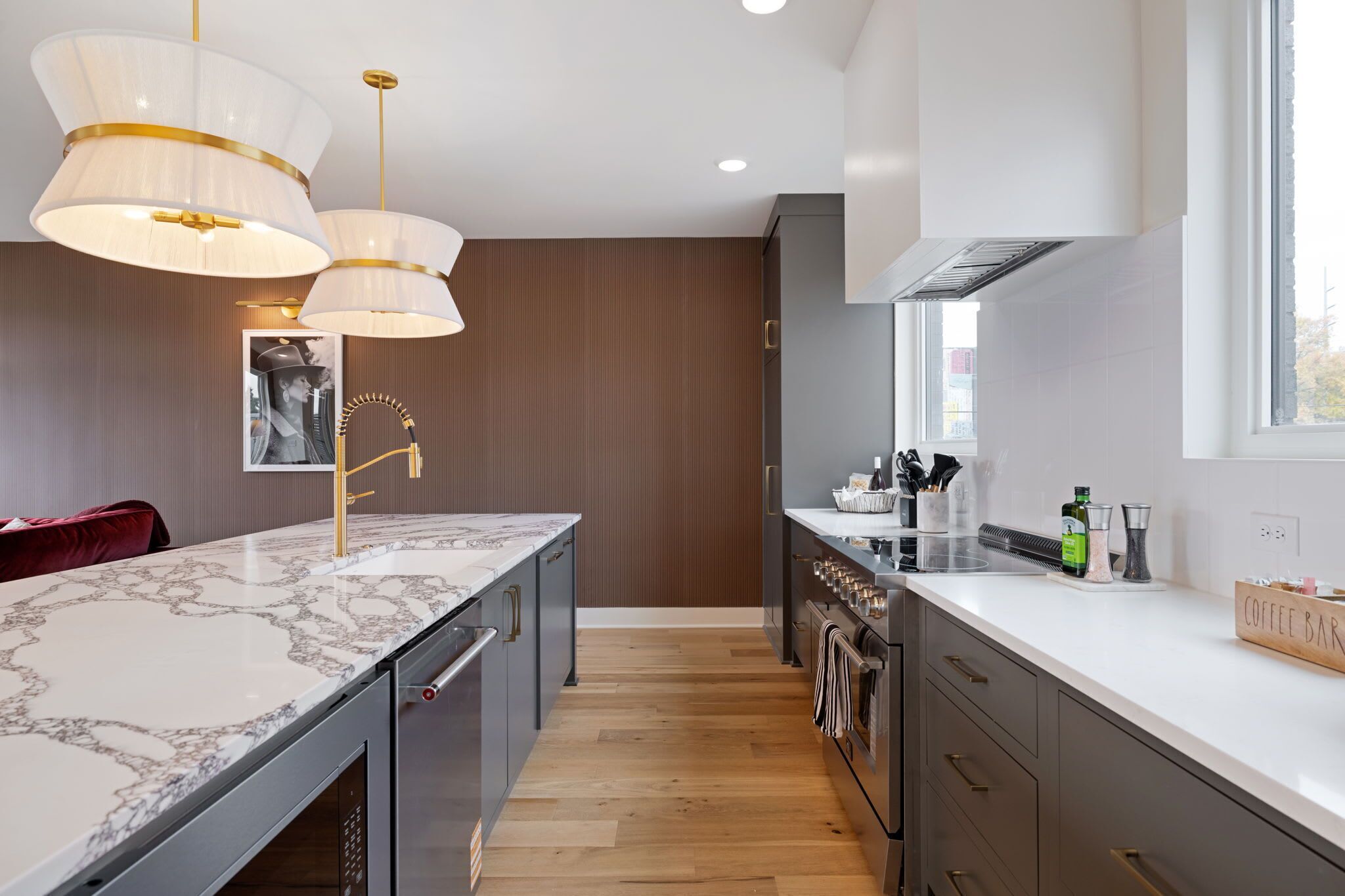 A modern kitchen with a marble countertop, stainless steel appliances, and pendant lighting.