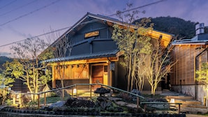 A traditional Japanese house with a wooden exterior, a tiled roof, and a stone lantern in the garden. - 1HOTEL (Shizuoka)