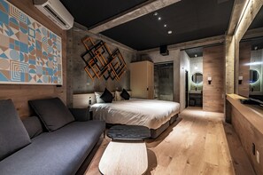 A modern bedroom with a large bed, a sofa, a small table, and a geometric wall decoration. - 1HOTEL (Shizuoka)