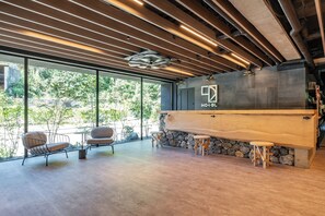 A modern kitchen with a stone wall, wooden counter, and bar stools. - 1HOTEL (Shizuoka)