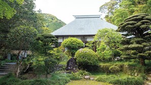 A traditional Japanese building surrounded by lush greenery and a stone staircase. - 1HOTEL (Shizuoka)