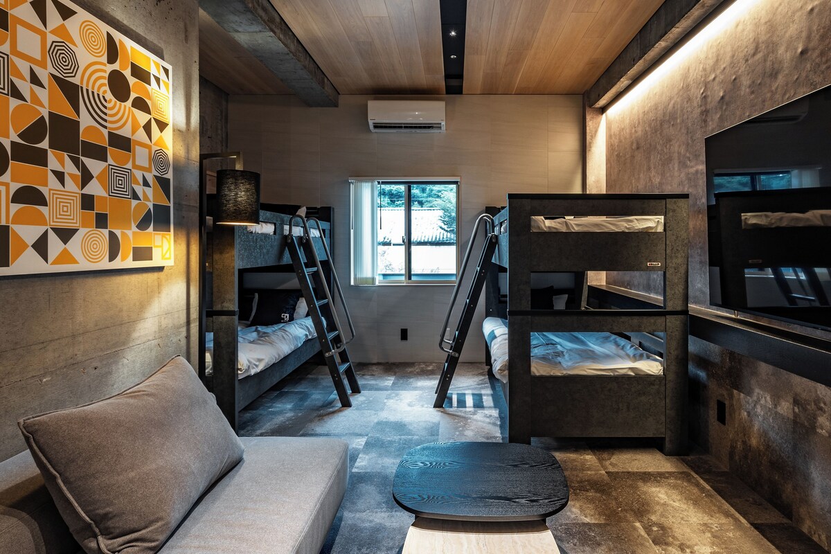 A room with bunk beds, a sofa, a ladder, and a patterned wall.