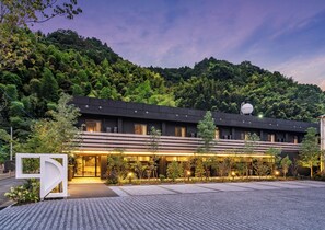 Un hotel moderno con techo plano, amplios ventanales y un espacio exterior bien iluminado con un camino pavimentado.