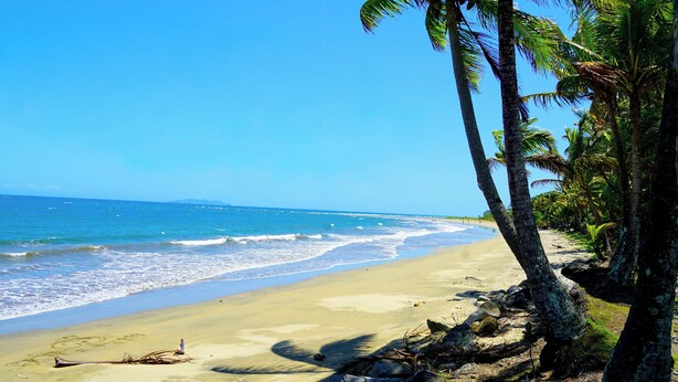 A beach with clear blue water, sandy shore, and palm trees. - Sunset Villas (Korotogo)