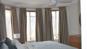 A bedroom with a bed, a ceiling fan, a dresser, and a window with curtains. - Hideaway on Seattle Dunsborough 5 minute walk to Quindalup Beach & pet friendly. (dunsborugh)