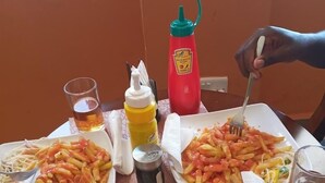A dining table with plates of food, condiments, and glasses of beverages.
