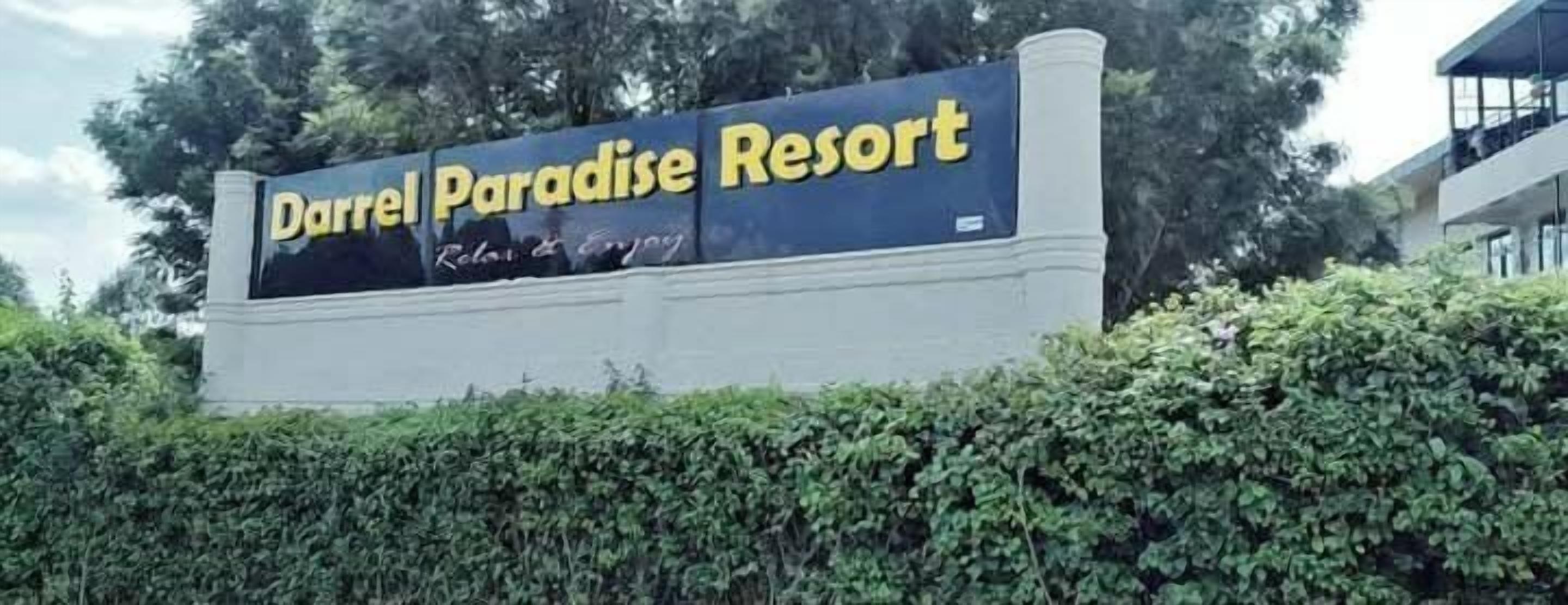 Une enseigne pour le complexe hôtelier Darrel Paradise Resort, sur laquelle on peut clairement voir le nom du complexe et son slogan.