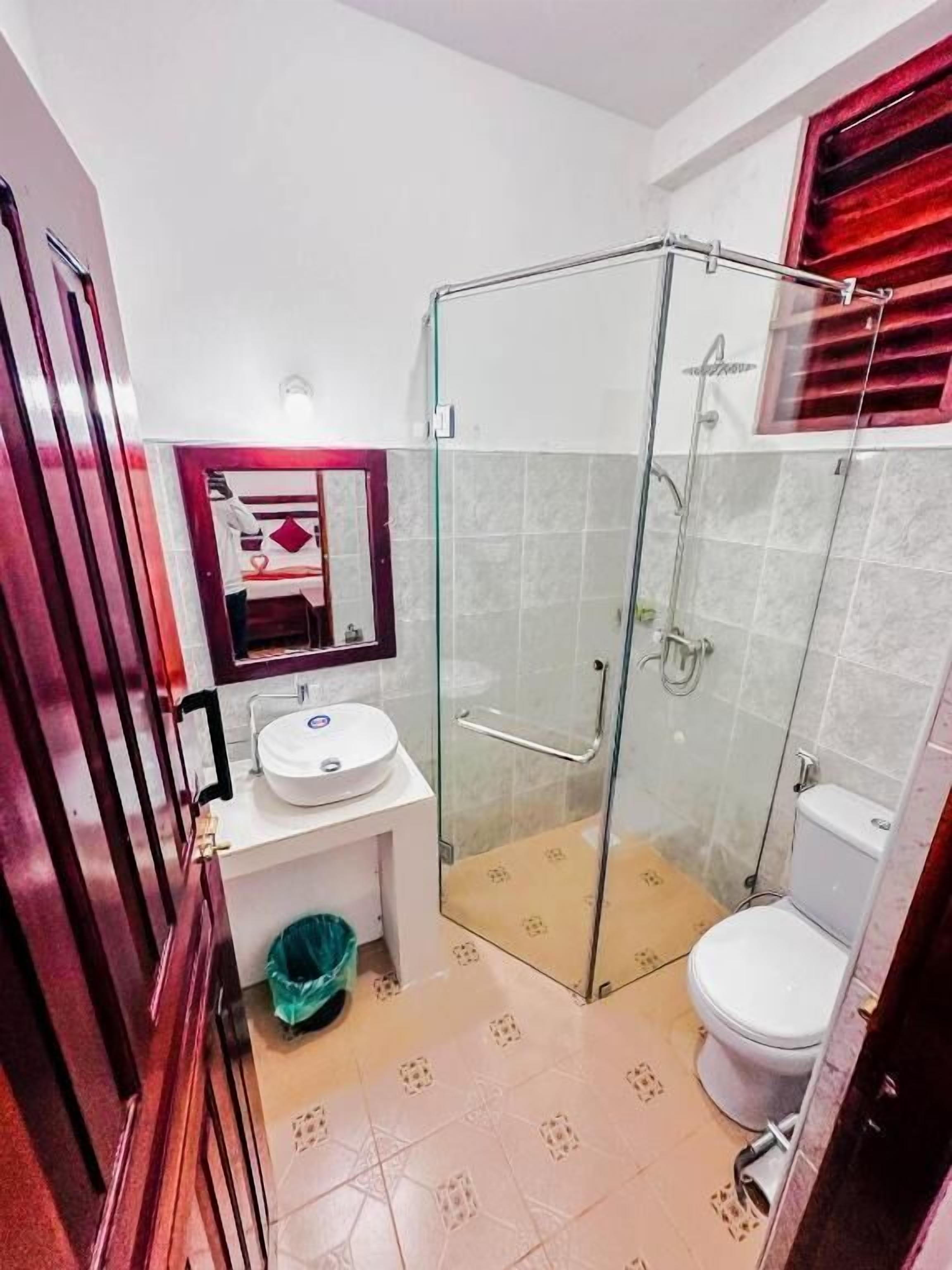 A bathroom with a glass-enclosed shower, a white sink, and a toilet.