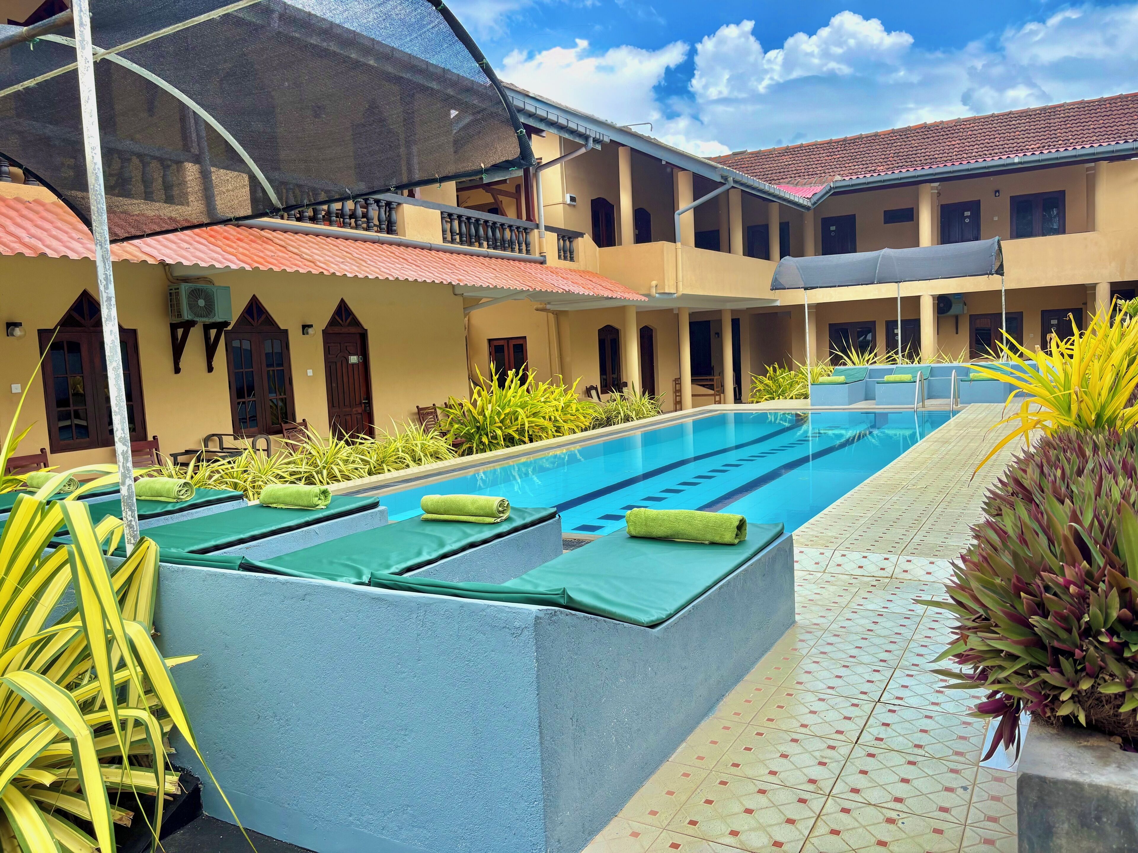 A swimming pool with lounge chairs and a covered area with a mesh roof.