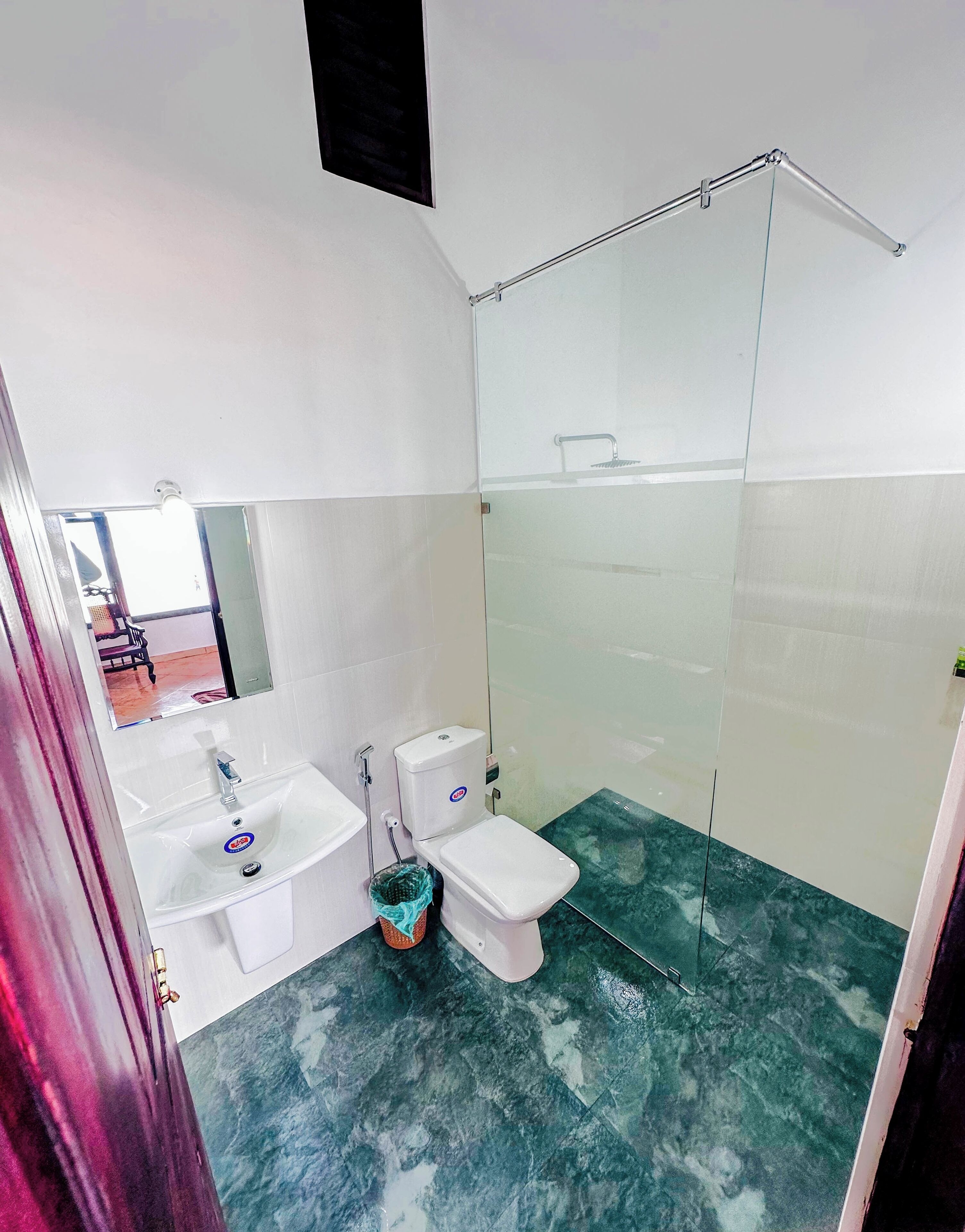 A bathroom with a glass shower enclosure, a sink, and a toilet.