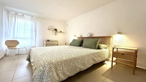 A bedroom with a bed, bedside tables, a chair, and a window with curtains.