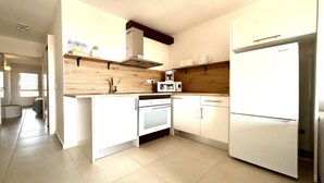 A modern kitchen with white cabinets, a built-in oven, a microwave, and a refrigerator.